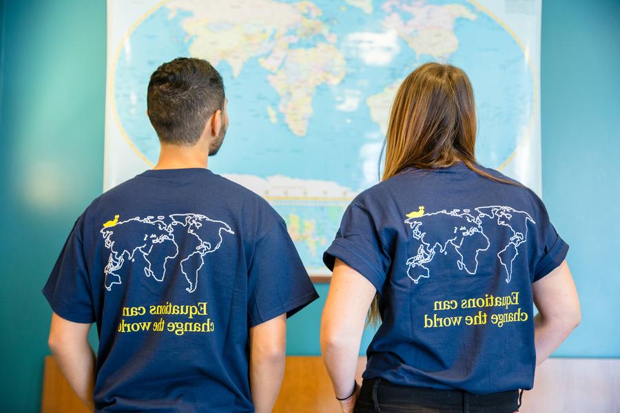 两个人在看地图. 他们穿着写着“方程式可以改变世界”的t恤.