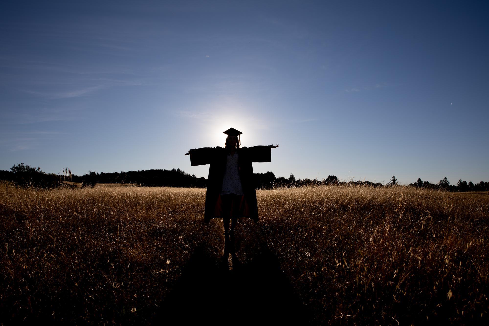 戴着帽子，穿着长袍，背着太阳站在田野里的人.